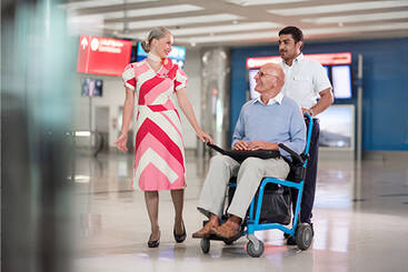 a marhaba representative and porter assisting an elderly passenger in a wheelchair 