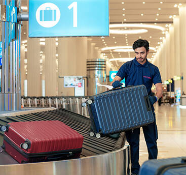 A marhaba representative removing a bag from a baggage belt in an airport