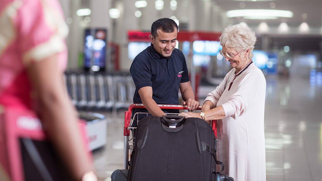 a marhaba representative assisting an elderly lady with her luggage